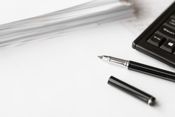 A black pen on a white background and a stack of paper. Flat simple business concept.