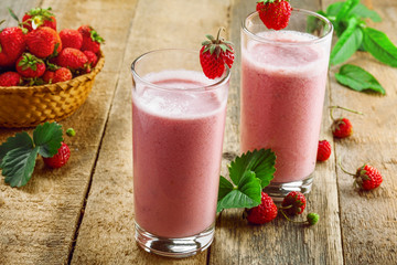Fresh strawberry milkshake on a wooden table. Healthy fruit smoothie drink.