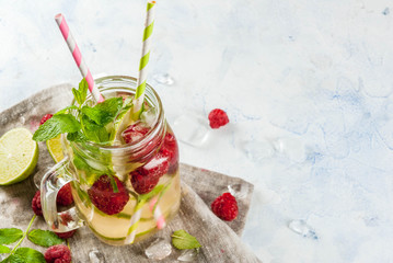 Summer drinks, cocktails. Vegan food. Infused detox water with lime, mint and fresh organic raspberries. On light concrete table, Copy space