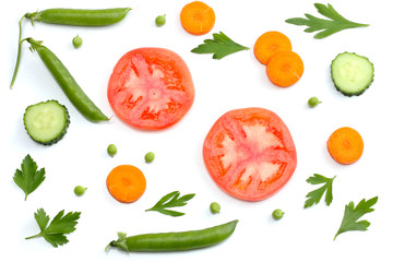 sliced tomatoes, sliced carrot, sliced cucumber, parsley and fresh green peas isolated on a white background. top view