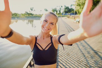 A smiling girl takes a photo  selfie on phone in the park.