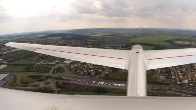 Aerotowing glider start and flight over urban landscape. Footage from action camera placed on aircraft elevator. Soaring under clouds.