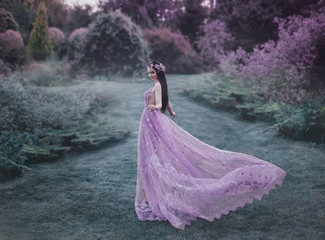 Fantasy girl in a fairy garden. Young elf in a beautiful purple dress with a long train. Creative...