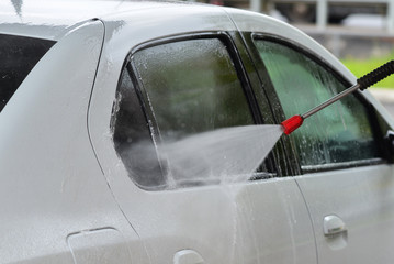 Car Wash Closeup. Washing white modern Car by High Pressure washer.