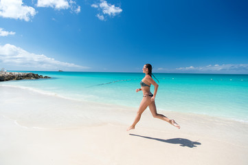 Fototapeta na wymiar Young woman running at the tropical beach