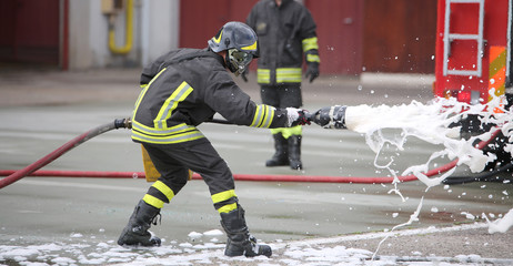 Naklejka premium Firefighters while extinguishing the fire with foam