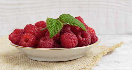 Raspberries in a bowl on a wooden white table