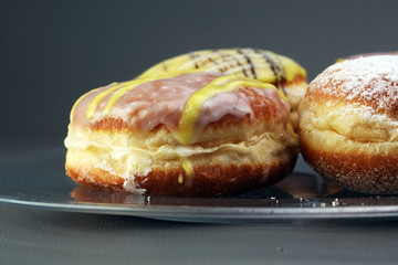 German donuts - berliner with jam and icing sugar in a tray on a grey background.