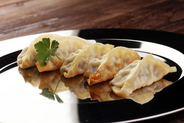 A plate of Japanese gyoza dumplings sitting on a rustic wooden table.