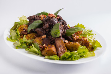 Warm salad with liver and apples on a white background