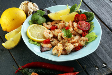fresh shrimps served on a plate with garlic onion, lemon and chili