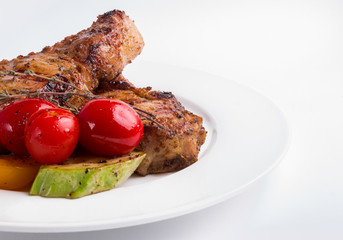 Grilled pork steak and vegetables on a white background