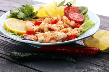 fresh shrimps served on a plate with garlic onion, lemon and chili