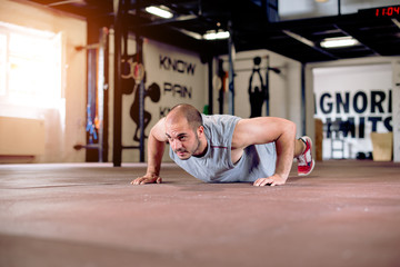 Fototapeta na wymiar Man is doing push ups in rustic gym