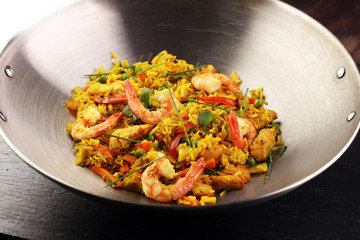 Udon stir-fry rice with shrimp and vegetables in wok pan on black burned stone background