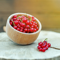 Tasty red currant in a wooden bowl. Useful berries. The concept is healthy food, vitamins, diet and vegetarianism.