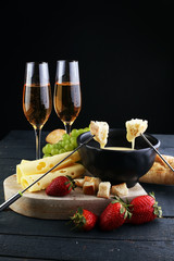 Gourmet Swiss fondue dinner with assorted cheeses on a board and