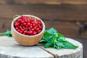 Red currant in a wooden bowl. The concept is healthy food vitamins diet and vegetarianism.