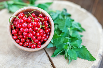 Tasty red currant in a wooden bowl. Top view. The concept is healthy food, vitamins, diet and vegetarianism.