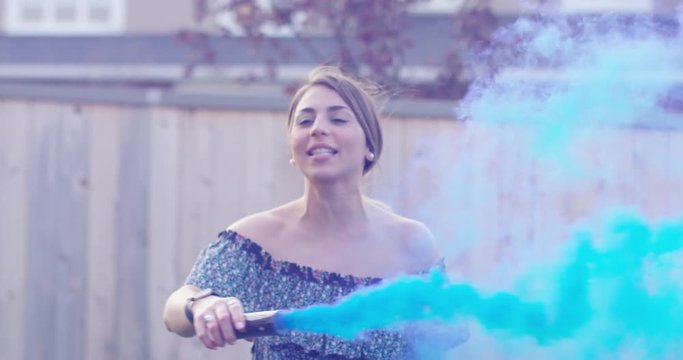 millennial woman dancing with blue smoke bomb - slow motion