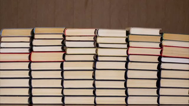 Books timelapse. Stacked books on wooden background. Time lapse of a growing stack of hardcover books