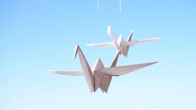 Origami crane. Origami birds on a blue sky background