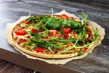 Hot true ITALIAN PIZZA with basil, arugula and cheese. TOP VIEW Tasty traditional pepperoni pizza on board on wooden table with decoration
