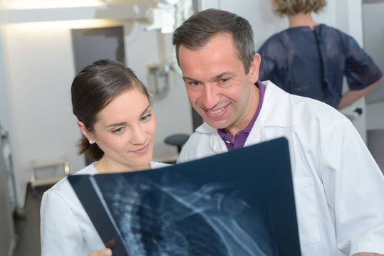 medical and radiology concept - two doctors looking at x-ray