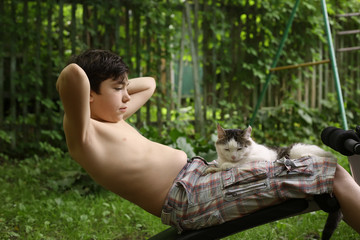 Obraz premium teenager boy make push up stomach exercise work out with cat on portable trainer outdoor summer photo