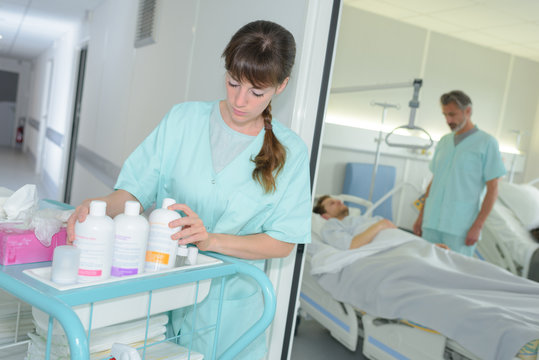 young female nurse with cleaning product on trolley at hospital