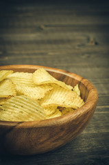 tasty potato chips in a wooden plate/tasty potato chips close up on a wooden background