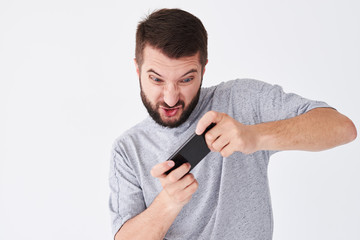 Emotional young bearded man playing games on smatphone