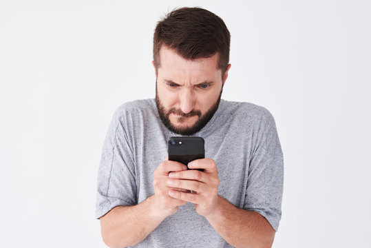 Excited bearded man in checked shirt playing on smartphone