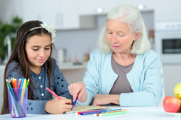 Fototapeta premium portrait of little girl with grandmother drawing with pencils