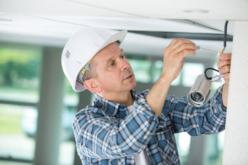 a mature professional handyman replacing light bulb