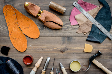 Working place of shoemaker. Skin and tools on brown wooden desk background top view copypace