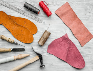 Working place of shoemaker. Skin and tools on grey wooden desk background top view