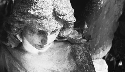 Vintage image of a sad angel on a cemetery against the background of leaves