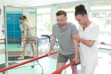 man on treadmill with therapist crouching in fitness studio