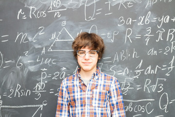 Teenager Boy in glasses, blackboard filled with math formulas background