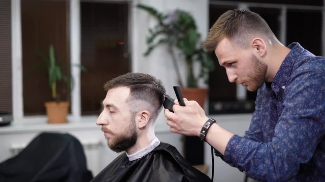 A visitor to the barbershop came to get a stylish hairstyle in barbershop, an adult man expects the hair to be trimmed