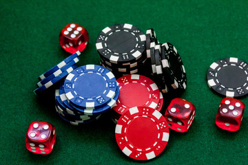 Poker chips and dice on a green gaming table top view close up