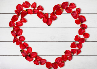 Obraz premium heart shape frame of red petals on white wooden table background