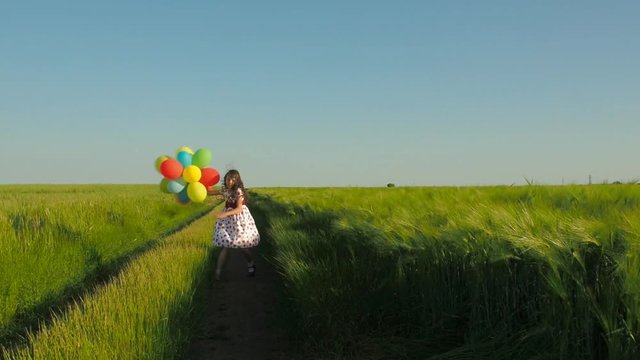 A little girl with balloons is spinning. Beautiful girl with balloons in nature.