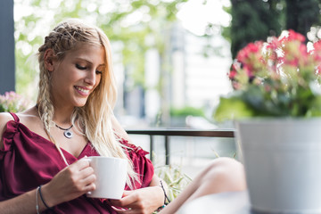 Beautiful blonde woman drinking a cup of coffee in a terrace