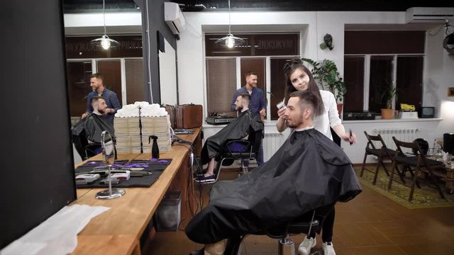 In a fashionable barber shop there is a haircut of several visitors, men are waiting for the end of their haircuts and hair styling with the help of gel and other styling