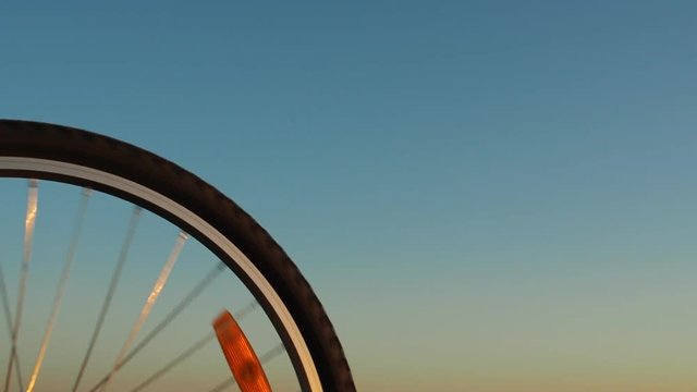 The wheel of a bicycle. A spinning bicycle wheel against the sky.