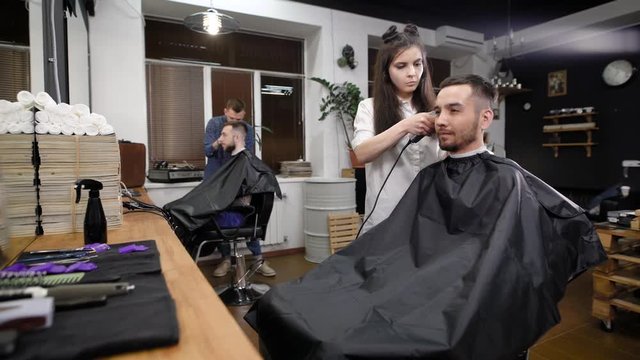 A young and fashionable woman hair stylist is trimming the hair of the lower part of her head for a beauty salon, the client expects good service and a neat hairstyle