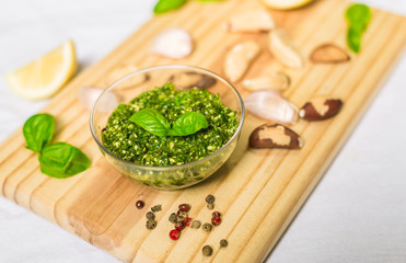 Basil and cheese pesto on a wooden board against white background