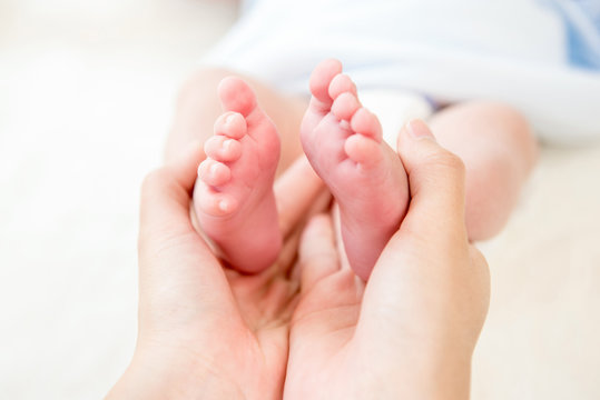 Mother hands gently holding small baby feet